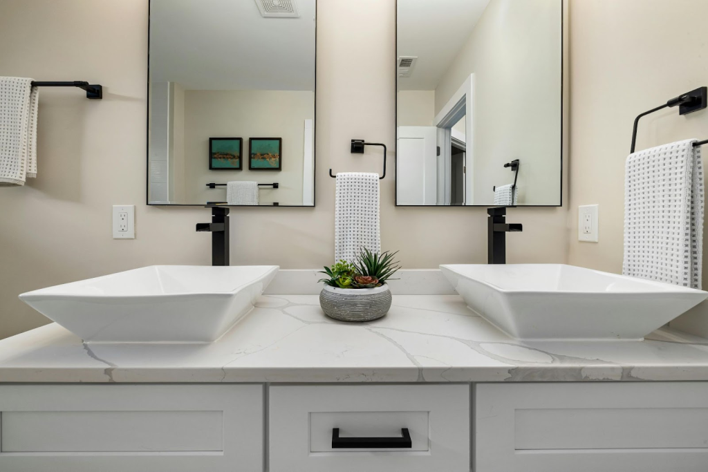 Two black vessel sink faucets in a bathroom with huge mirror